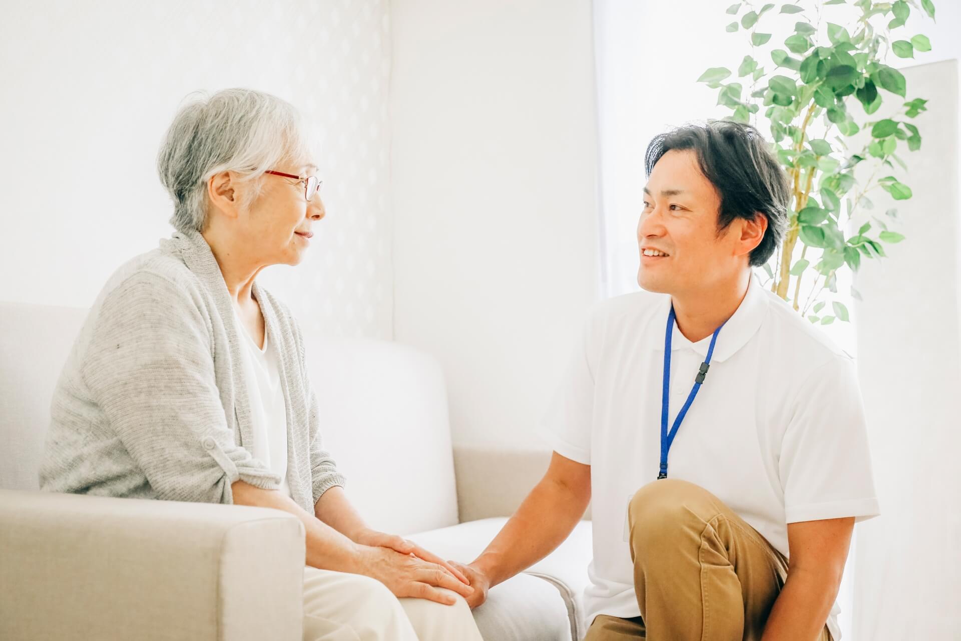 高齢者と目線を合わせて話す男性スタッフ